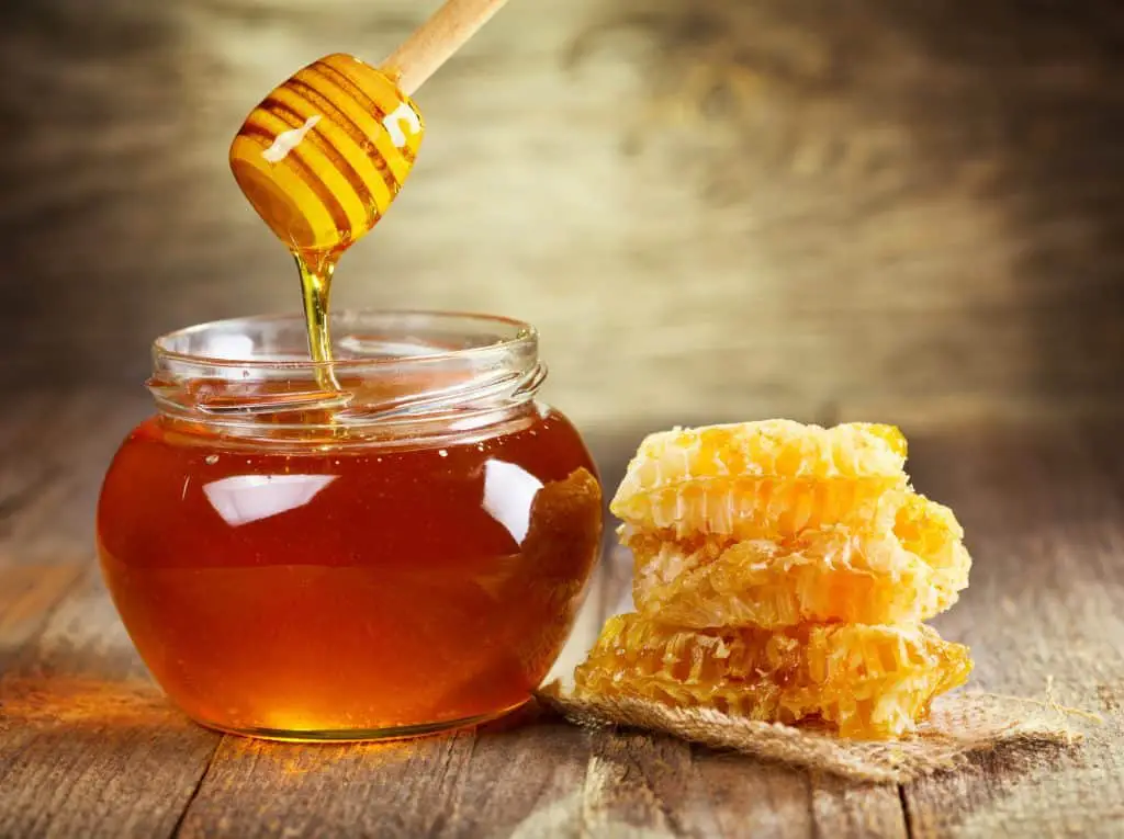 Jar of honey next to honeycomb