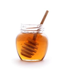 honey in a jar with a sturer in it