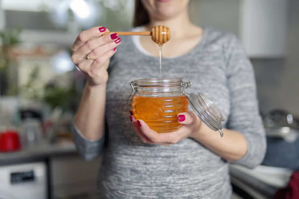 girl eating honey out of a jar