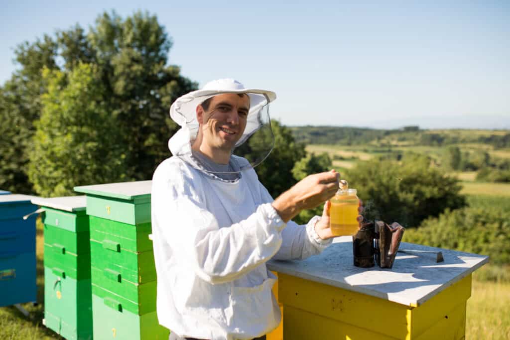 guy pouring honey into hive