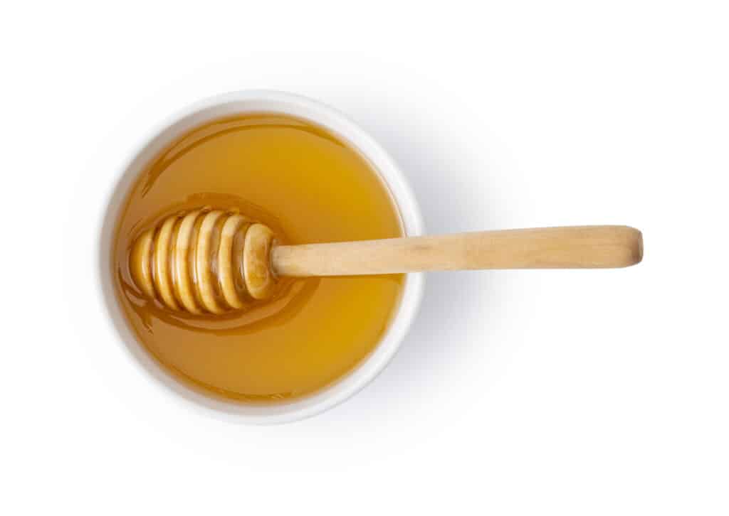 honey in a cup with a wand